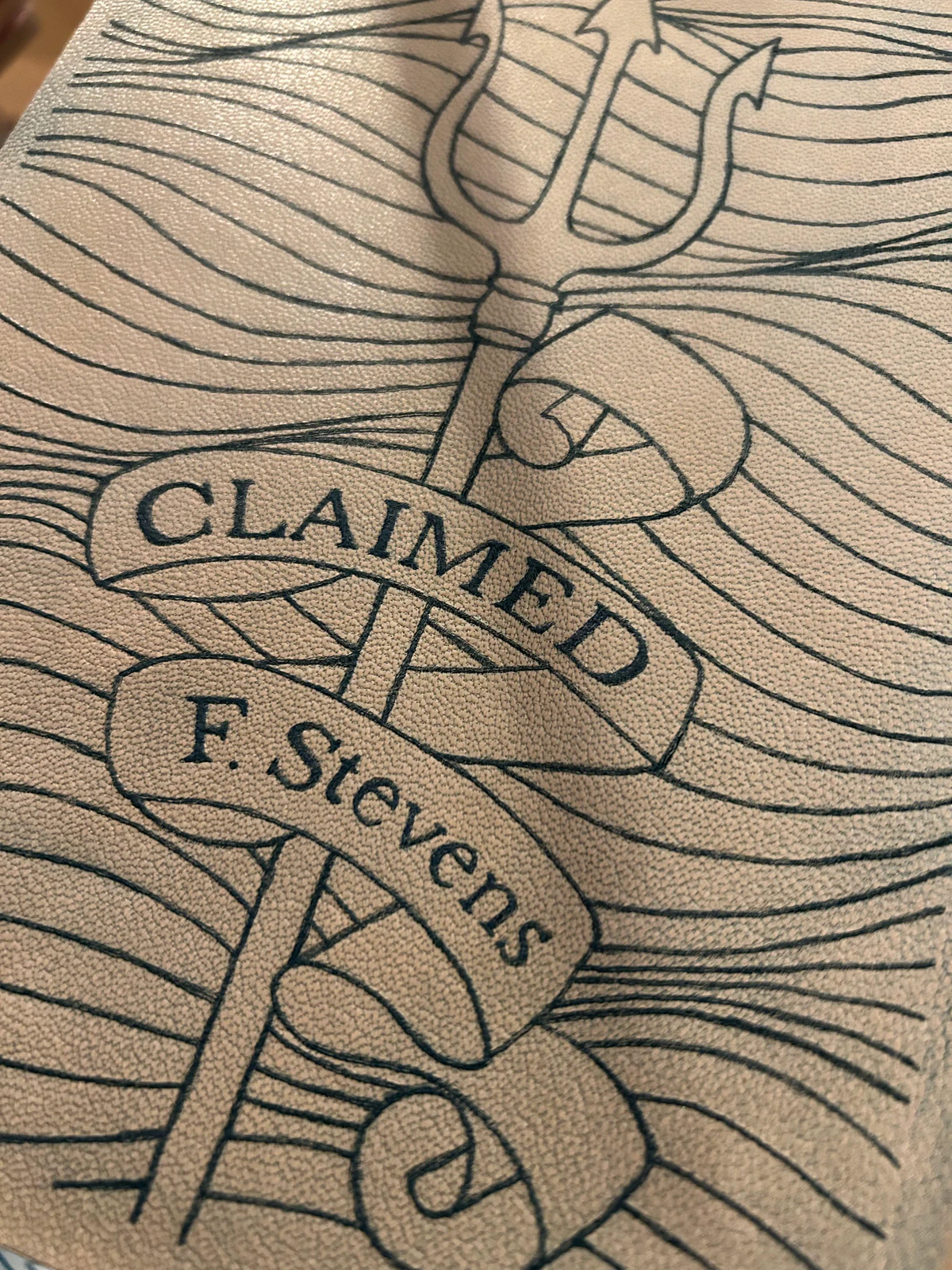 Tattooed leather for Claimed: a trident with banners reading Claimed and F. Stevens over wave lines