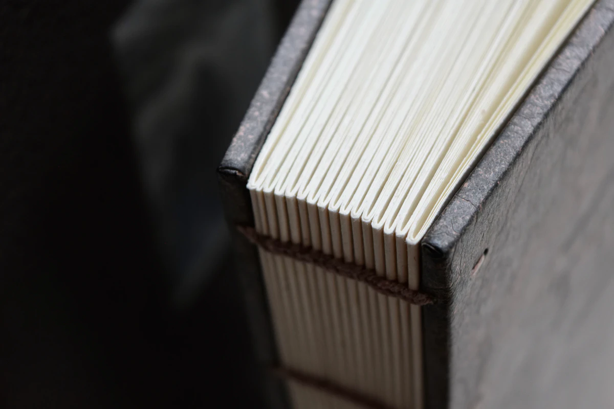 The open Coptic binding of the lettered The Road from Suntup Editions, sewn sections against a slate board